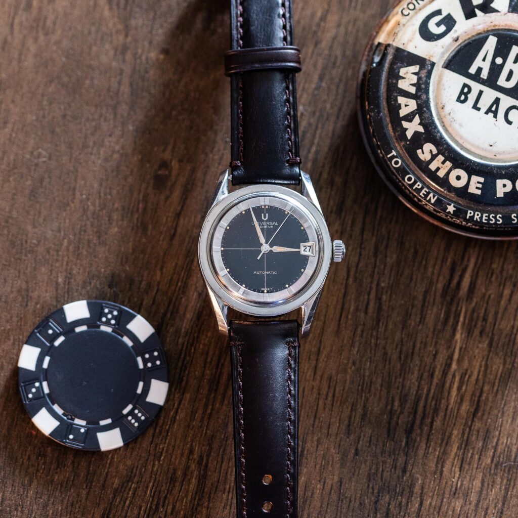 Universal Genève Polerouter Date with black crosshair dial photographed on a wooden surface.