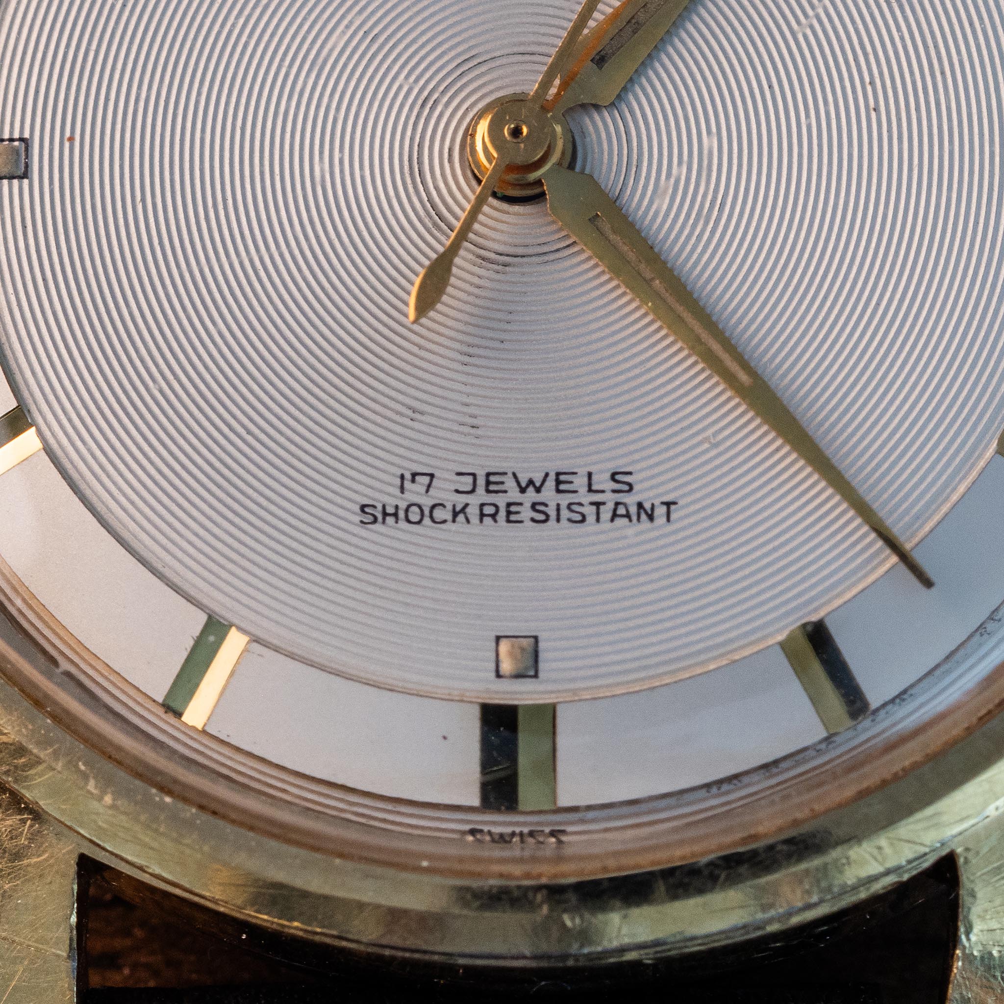 Macro view of the Waltham silver concentric-texture dial showing gold hands, applied markers and 17 JEWELS SHOCKRESISTANT text.