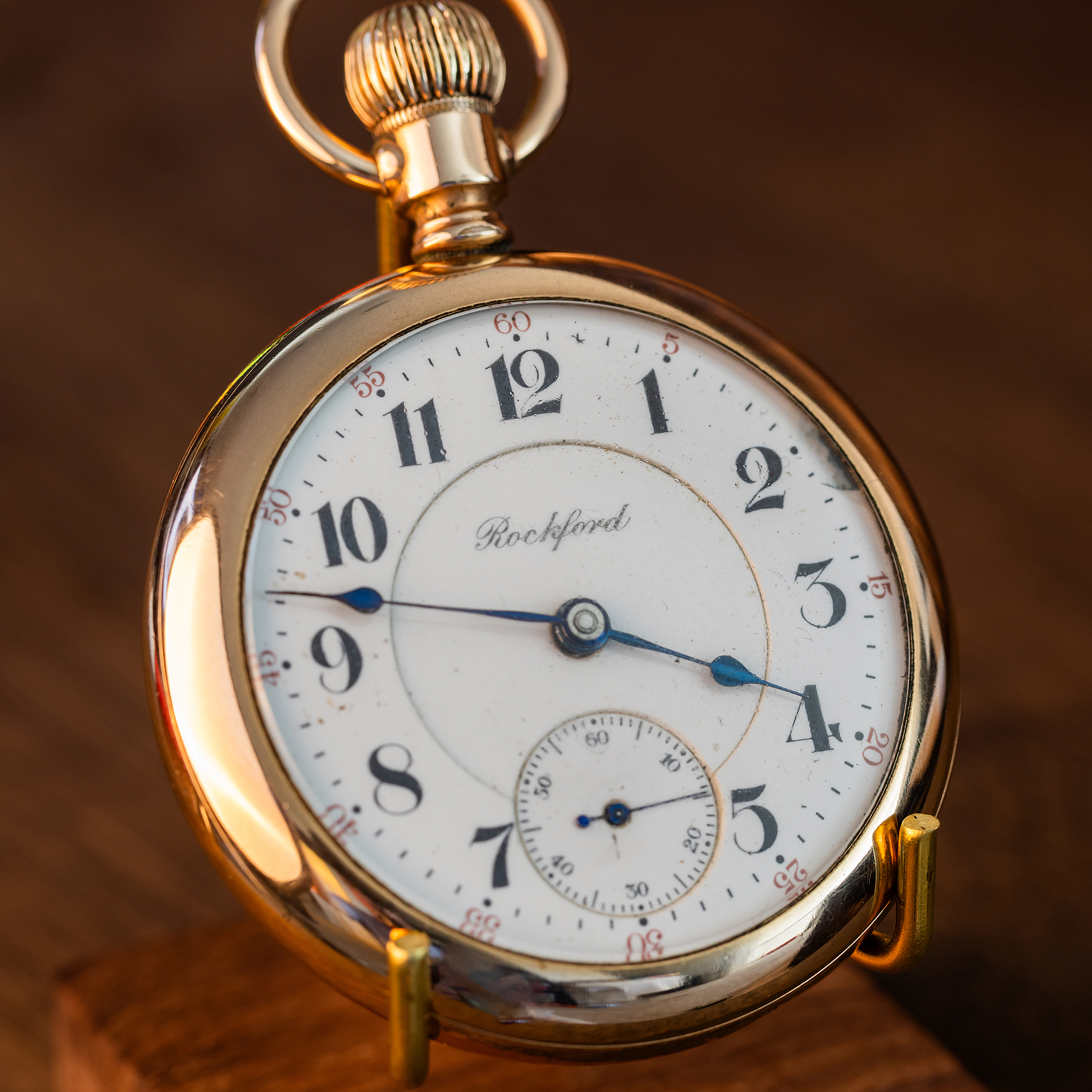 Angled view of antique Rockford Grade 918 pocket watch showing the heavy gold-filled open-face case, winding crown, bow and enamel dial