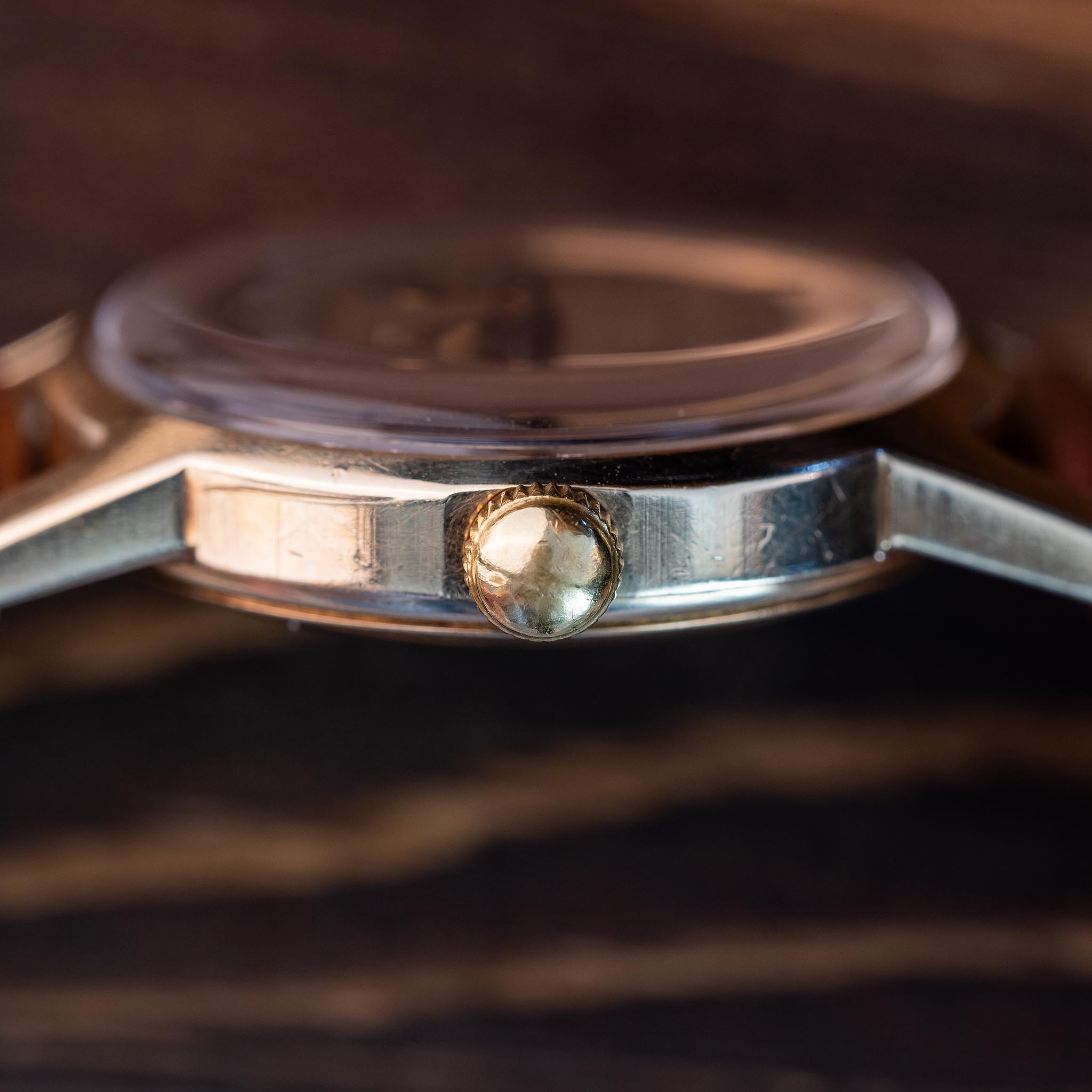 Profile of compact 10K gold Croton Aquamedico watch case and domed fluted winding crown beneath raised crystal