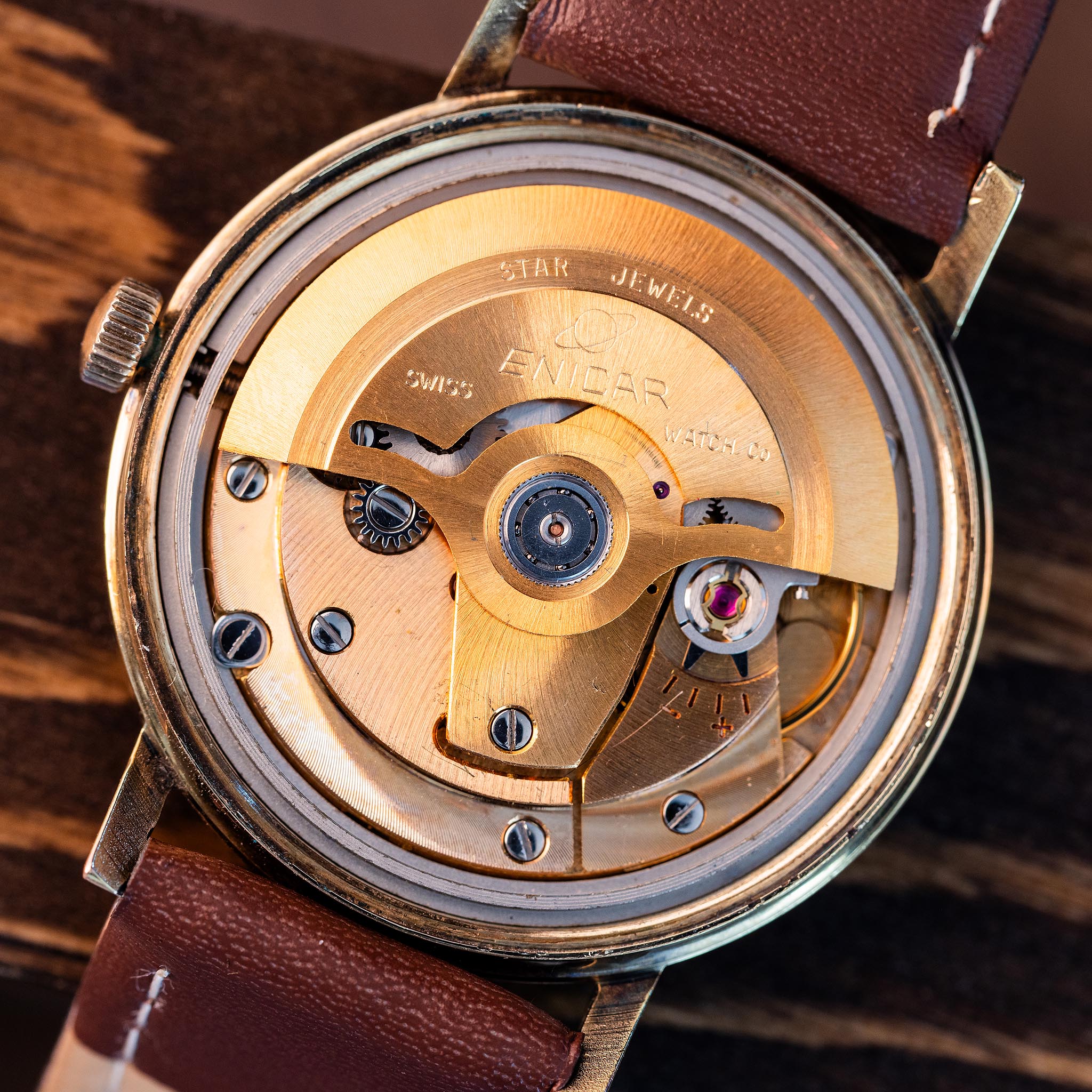 Close-up of Enicar Star Jewels automatic signed gold-tone winding rotor and Swiss mechanical movement with visible gear train