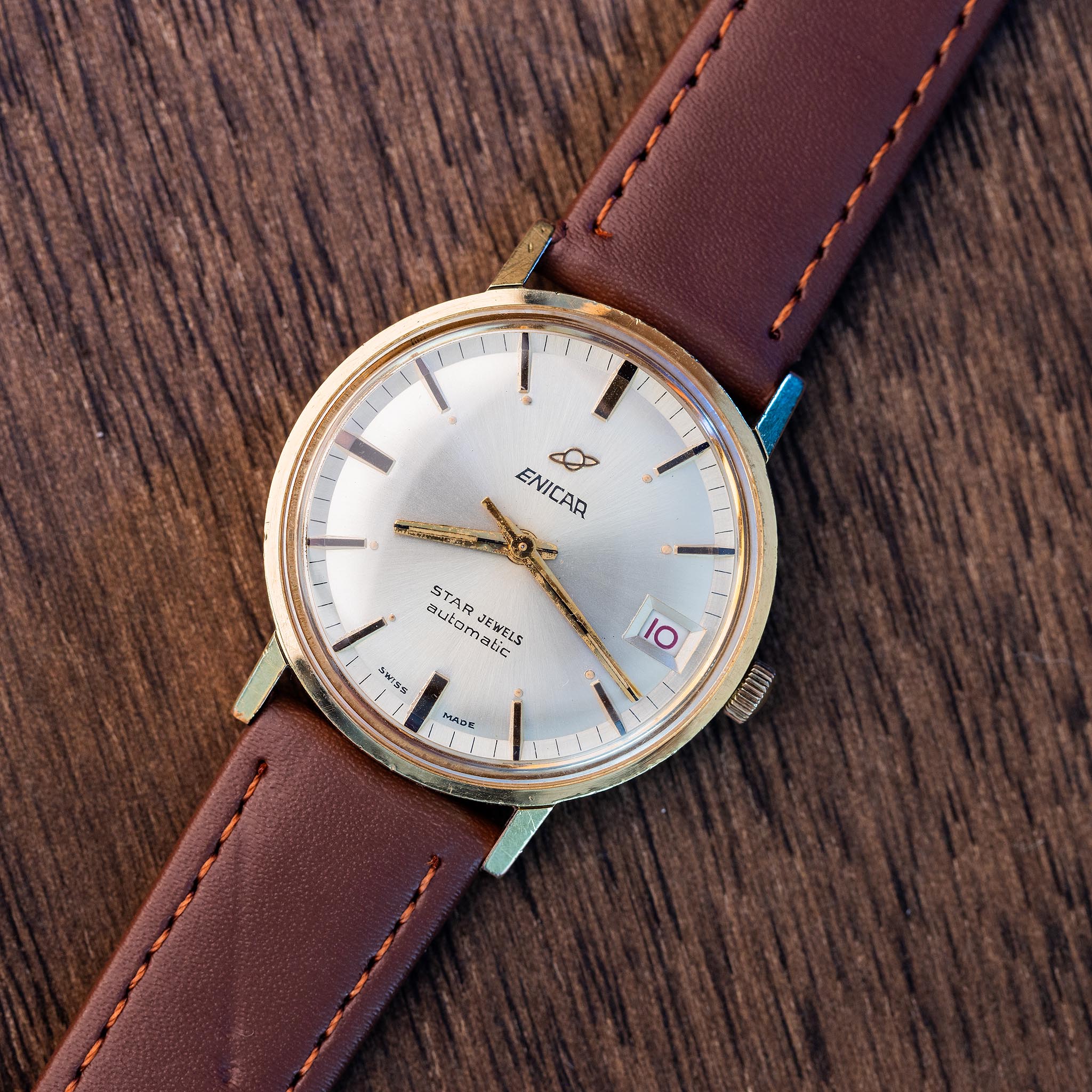 Enicar Ocean Pearl Star Jewels vintage automatic watch with silver sunburst dial and brown stitched strap.