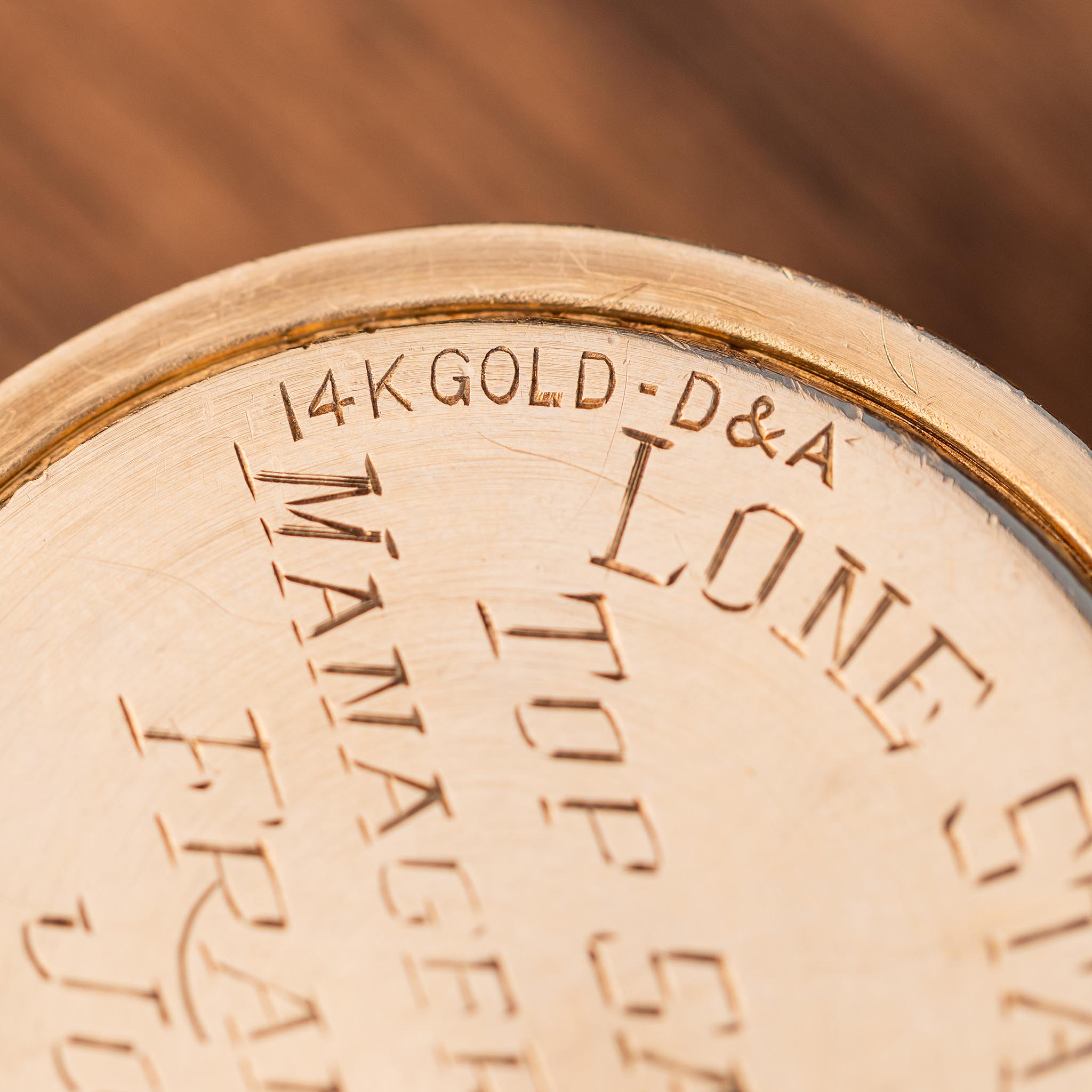 Close-up of a vintage 14K gold watch case back engraved with D&A, LONE STAR, and partial text reading TOP SALES MANAGER.