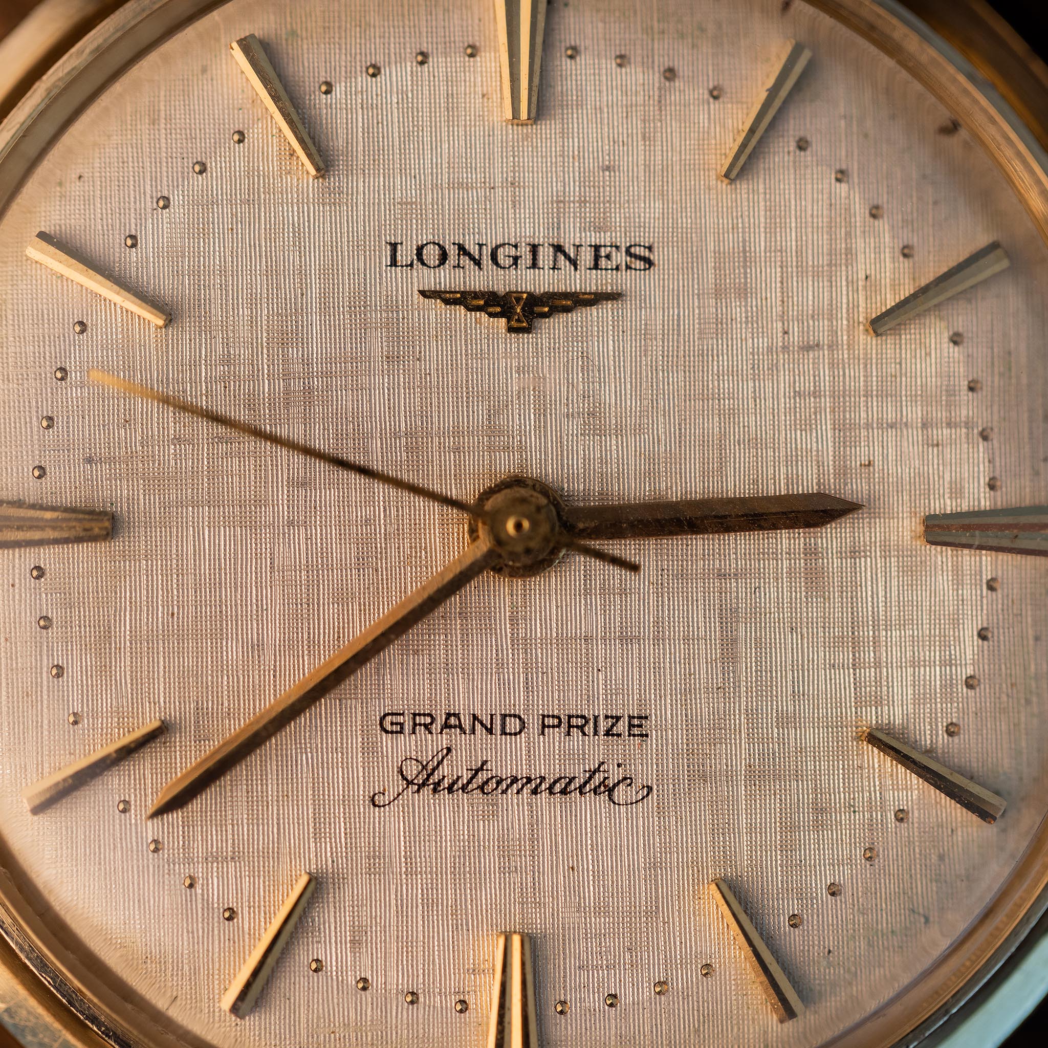Close-up of a vintage Longines Grand Prize Automatic 340 watch face with a textured dial and gold-tone hands.