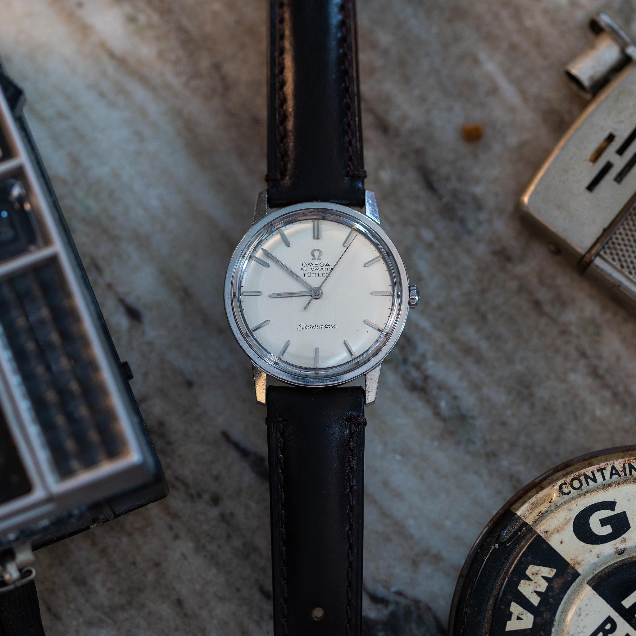 Omega Seamaster Türler reference 165.002 photographed on a marble surface with vintage objects.